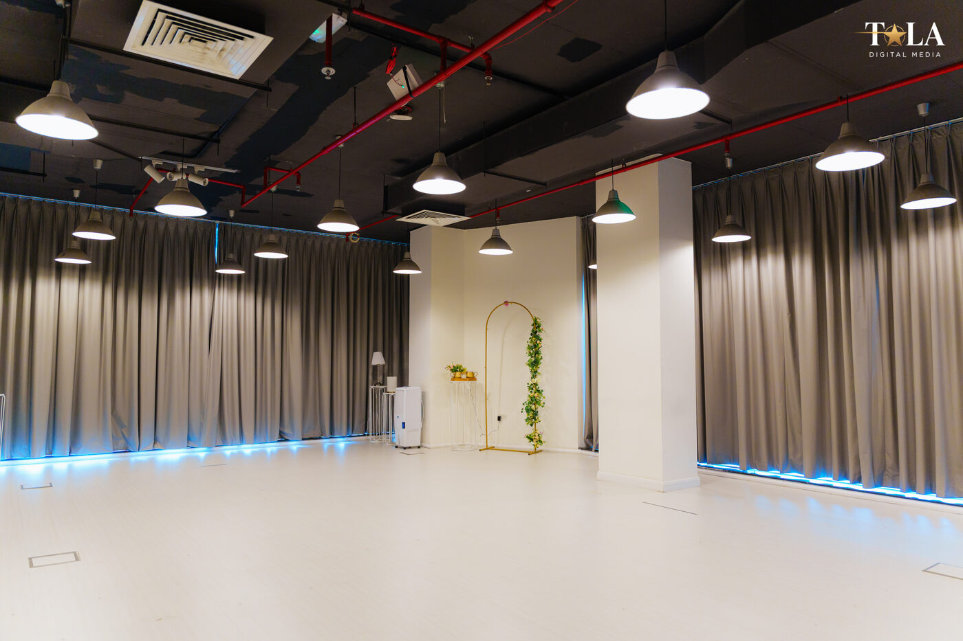Wide studio floor with curtain backdrop, blue accent lighting, and event styling